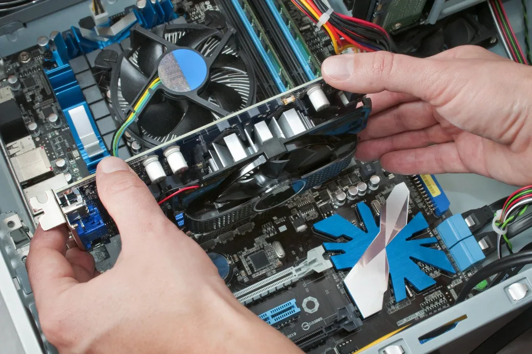 Hands installing a graphics card into a desktop computer